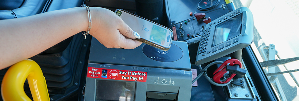 a picture of someone using tap to pay on their phone to pay their bus fare.