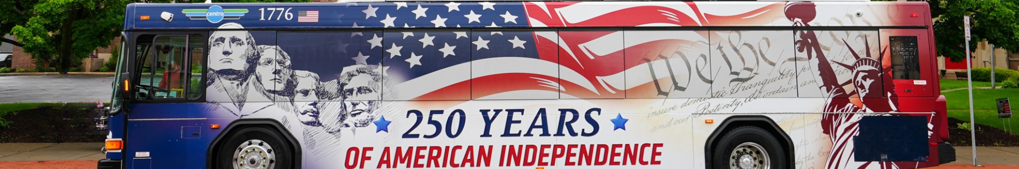 A bus with an illustration of Mt. Rushmore and Lady Liberty in front of an American Flag. Text reads: '250 Years of American Independence'.